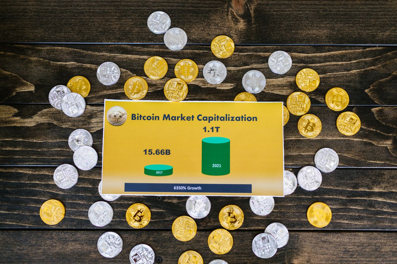 Bitcoin coins on wooden surface with chart showing market cap growth to 1.1T.